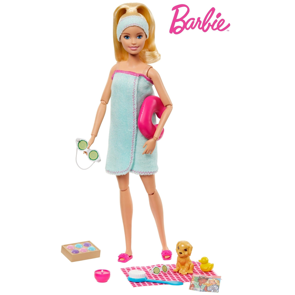 Image of Barbie and all her things outside of the packaging. Her set includes Barbie in a towel, a neck pillow, cucumber glasses, a dog, a rubber ducky, a candle, and a magazine.