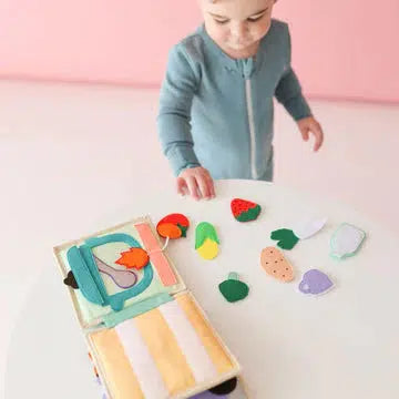 this image shows a child opening the book to play with fruit shaped items inside ot learn