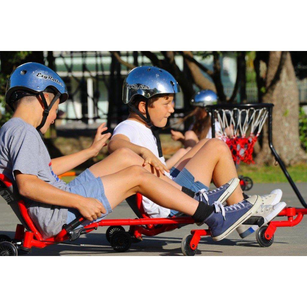 two boys are wearing helmets while using an Ezyroller. they are seated down and rolling around, having fun
