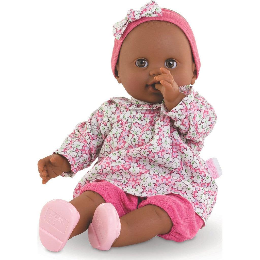 a baby doll is shown sitting up, she's dressed in a floral top, pink bloomers, a headband and light pink shoes
