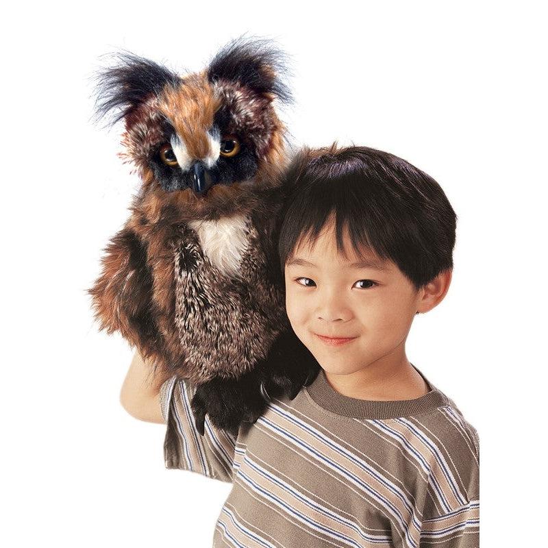 Young boy holds puppet on arm, resting it on his shoulder and smiling. 