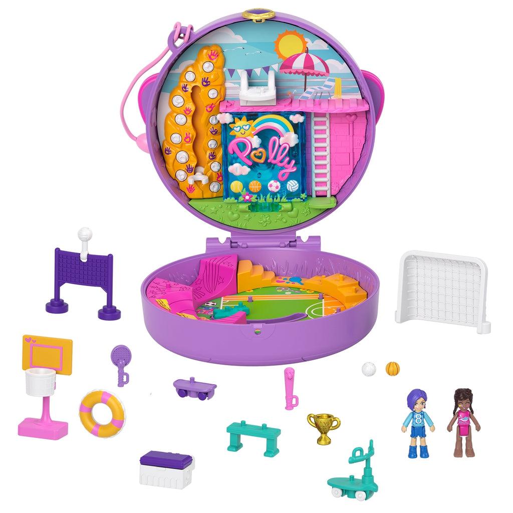 Image of all the included pieces outside of the packaging. The set includes two Polly Pocket dolls, the sports themed compact, volley ball net, soccer net, basketball hoop, scooter, tennis racket, benches, and trophies.