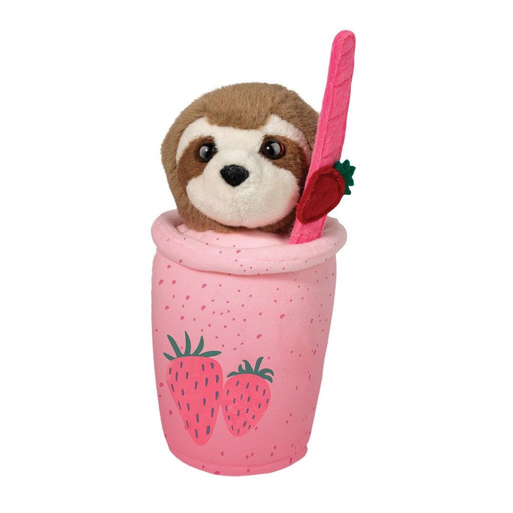 image shows a sloth  in a strawberry theres cup.. she is holding a straw to drink the pink strawberry smoothie