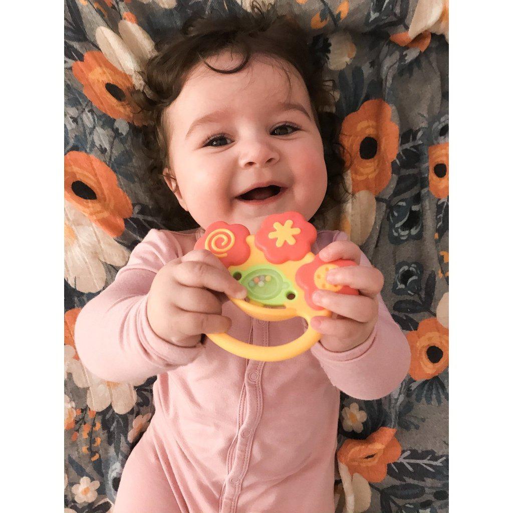 Scene of a baby girl smiling and holding the toy.