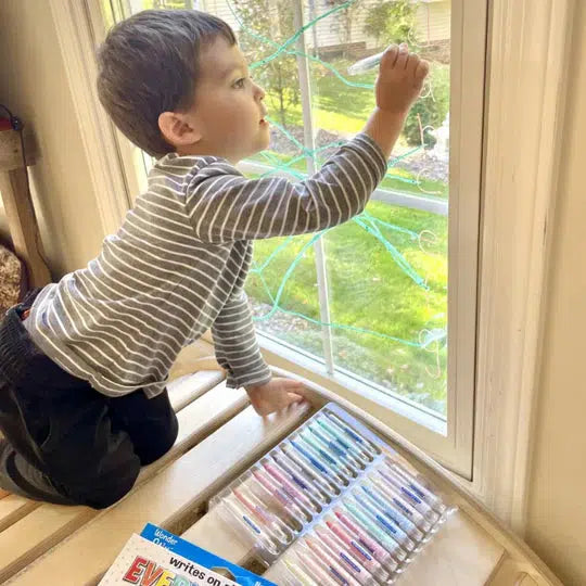 Scene of a little boy using the Wonder Stix to draw pictures on a window.