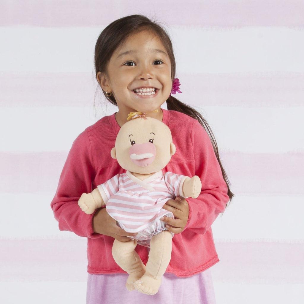 A child is shown smiling and holding the baby peach doll under her chin.
