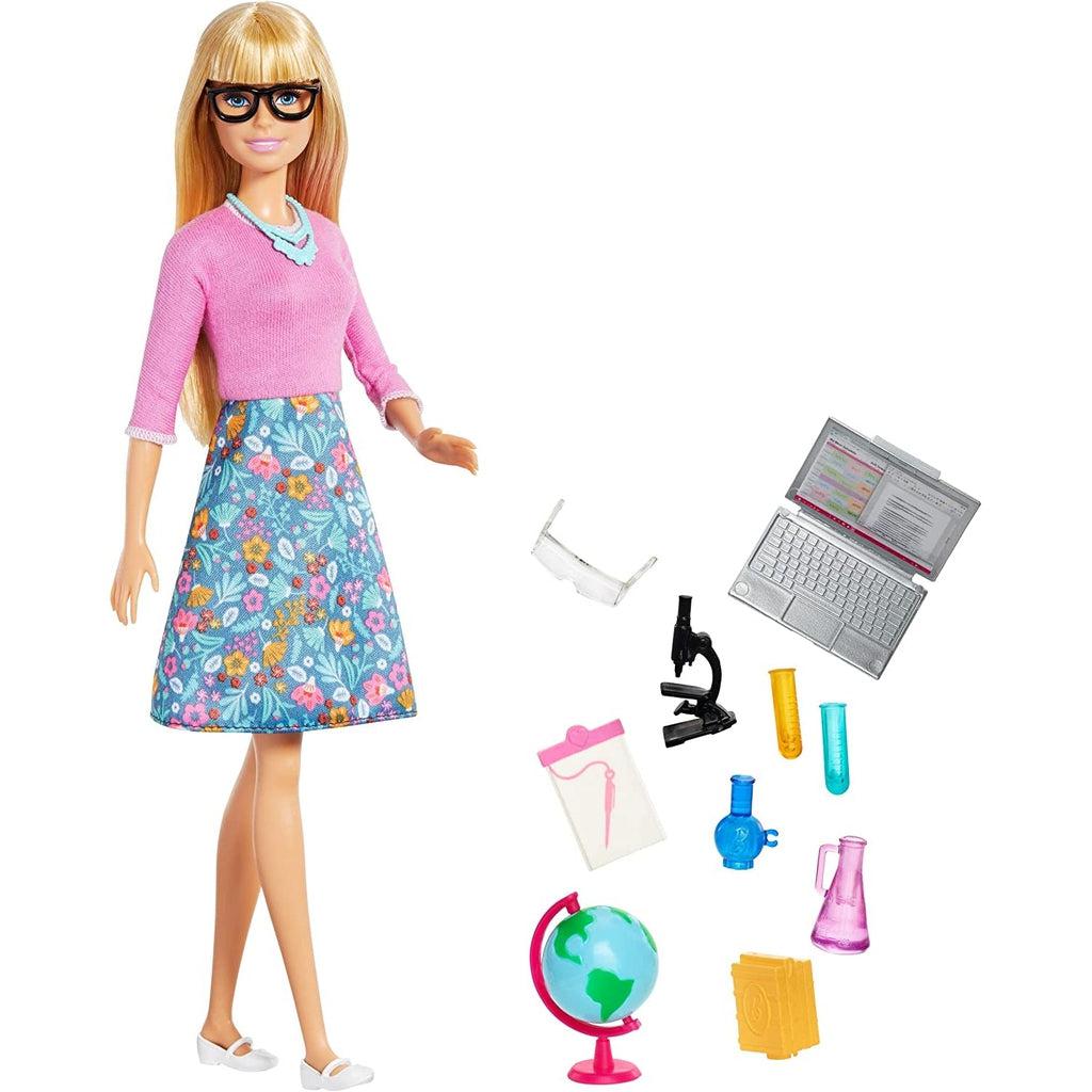 The barbie doll is shown out of packaging next to all the accessories. The doll has blond hair down to the waist, a pink long sleeved shirt, and a knee length skirt with a floral pattern on it. Accessories included are detailed in description.