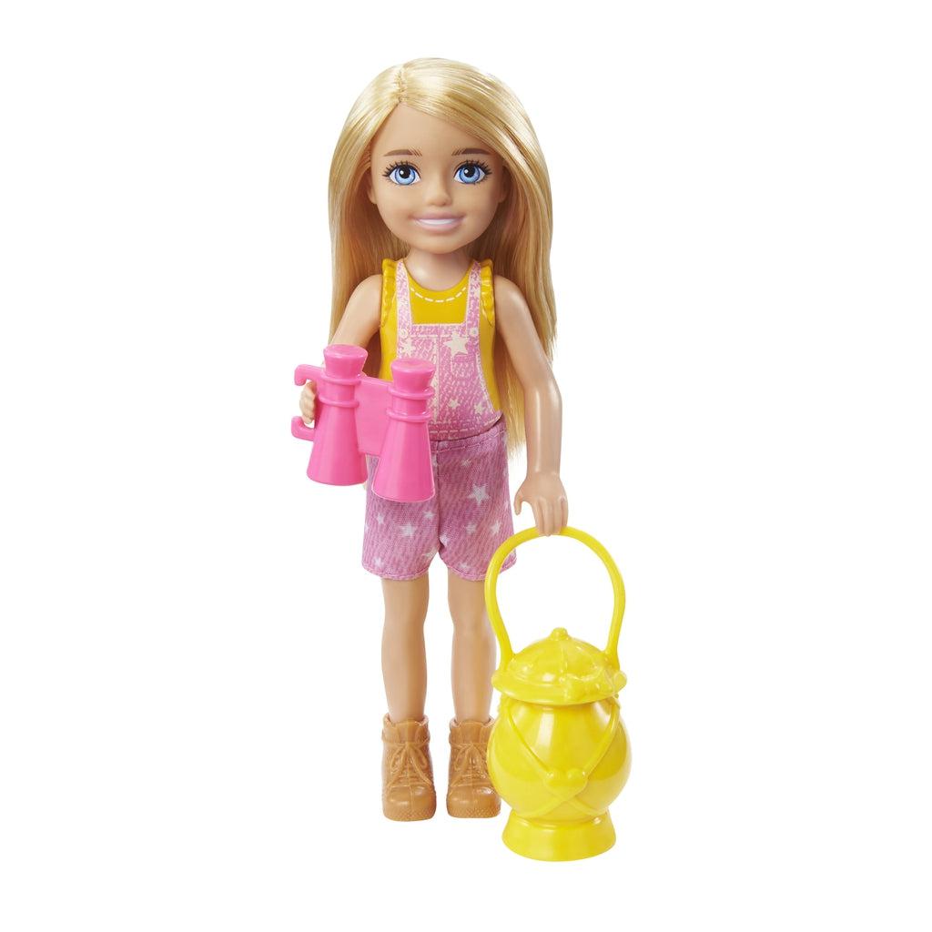 Chelsea doll is blonde with blue eyes | She is wearing a yellow tank top, pink overalls with white stars, and brown boots. | She is holding pink binoculars and a yellow lantern.