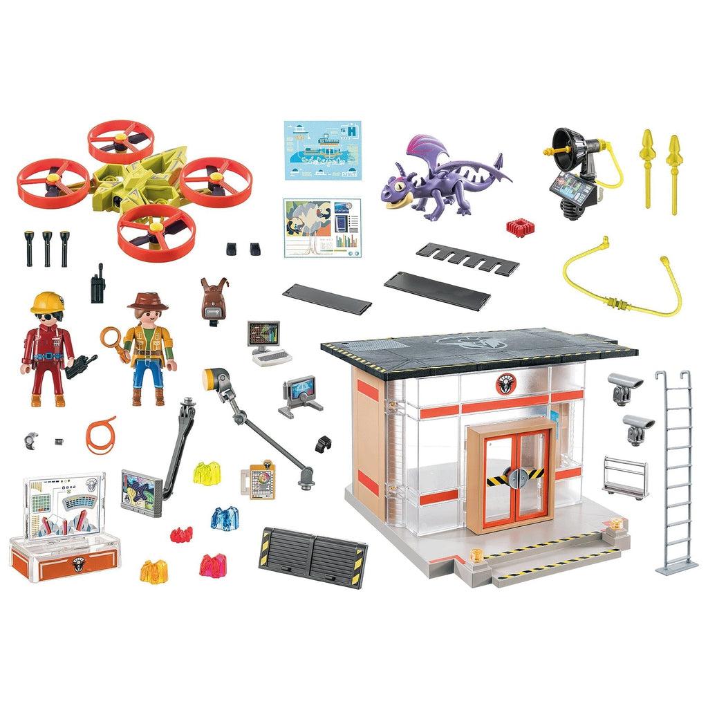 Image of all the included pieces outside of the packaging. The set includes the lab, two researchers, a small dragon, a ride-able drone, and various different research tools and materials.