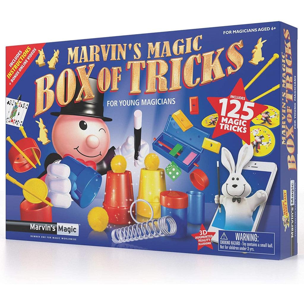 The front of the box shows marvin (a cartoon man with a round head) preforming a magic trick with 3 cups and balls. There are a variety of tricks displayed on the box in various states such as an open box with a pin going through blocks. The box reads: Marvins magic box of tricks for young magicians. Includes 125 magic tricks