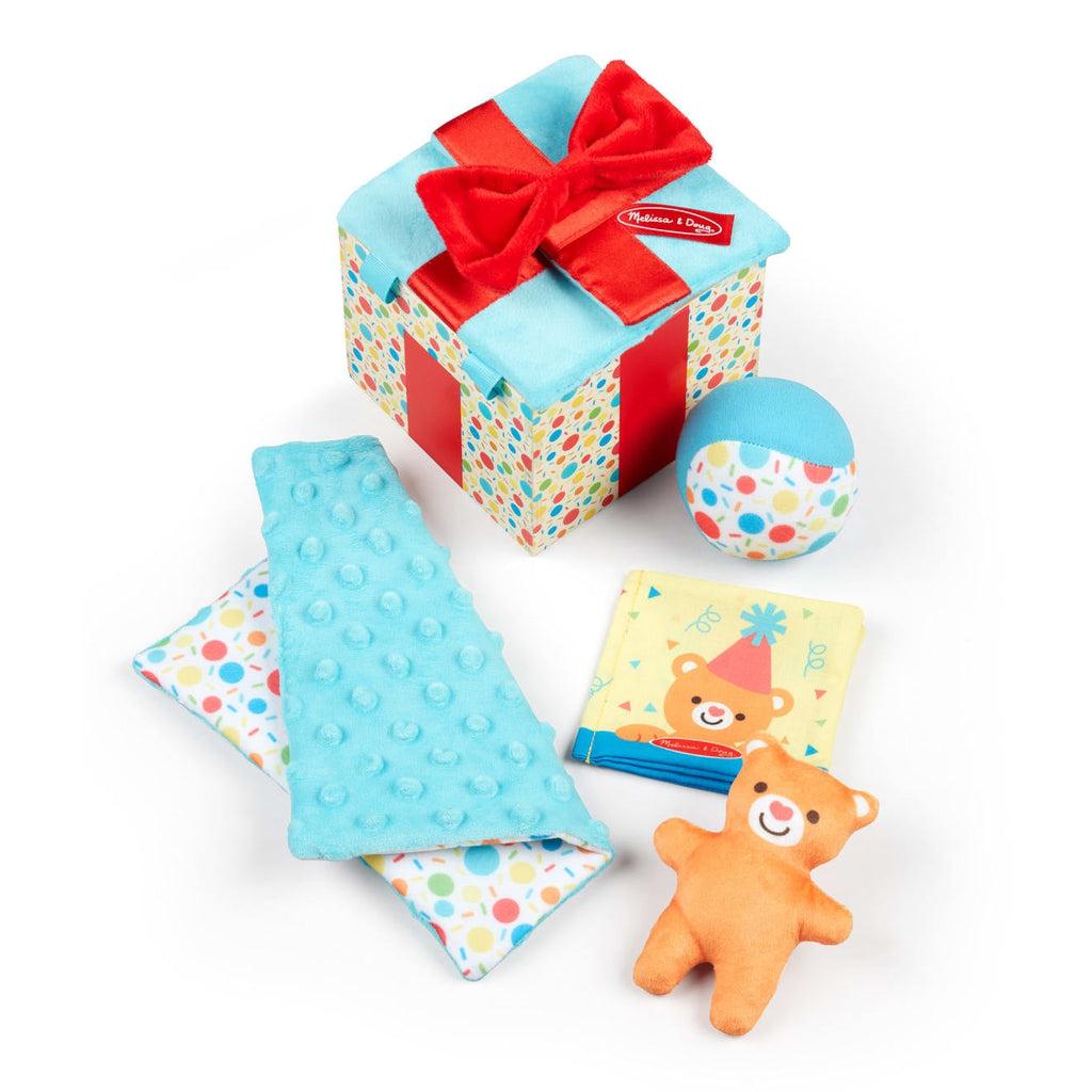 Toy out of package | Wooden box with colorful polka dot design, soft blue lid flaps and red soft bow | Contents of box are a multitextured crinkle blue and polka dot crinkle cloth, a brown plush bear, a squeezable blue and polka dot ball with chime, and a soft, cloth bear themed book