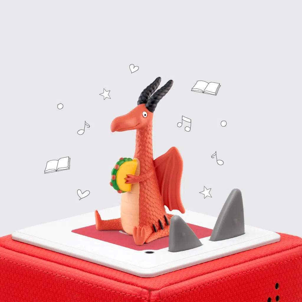 Tonie is an orange dragon sitting down with his legs out and tail wrapped around one side | dragon has long black horns and a long beak like snout | dragon is holding a taco