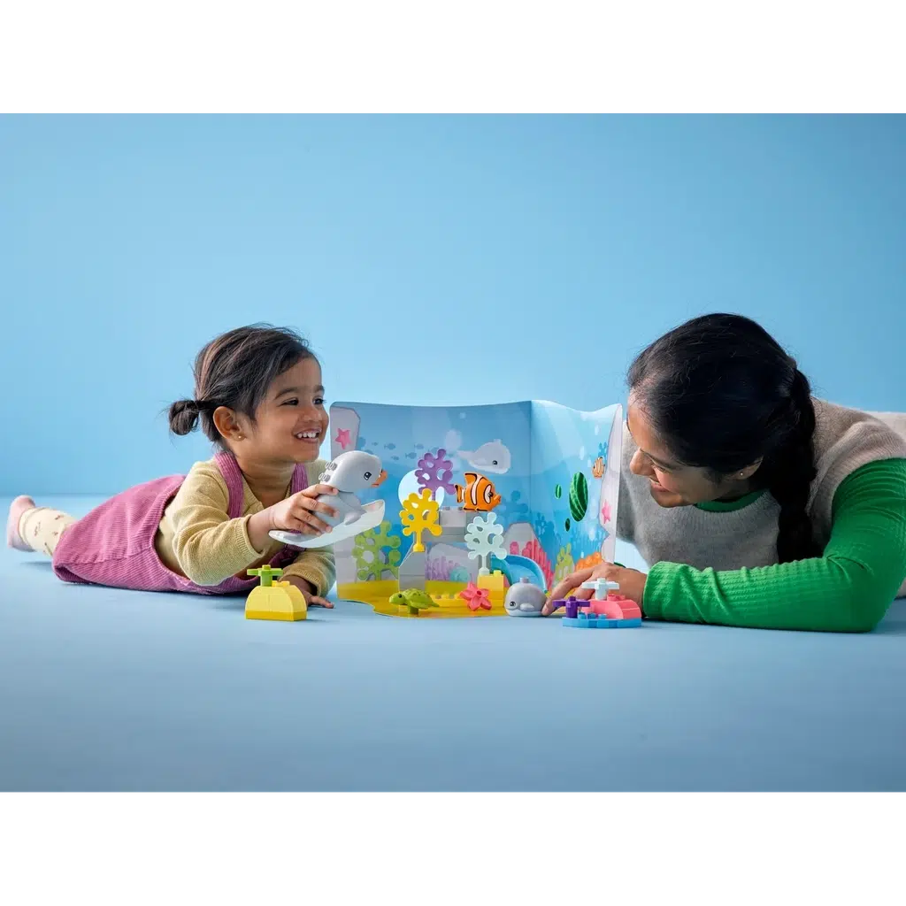 a mother and her toddler are playing with the duplo playset on a floor