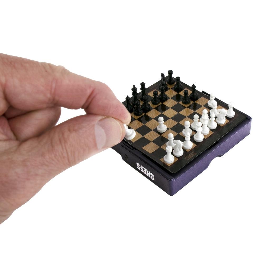 Shows a hand placing a game piece on the board for size comparison. The board is smaller than a child's palm.