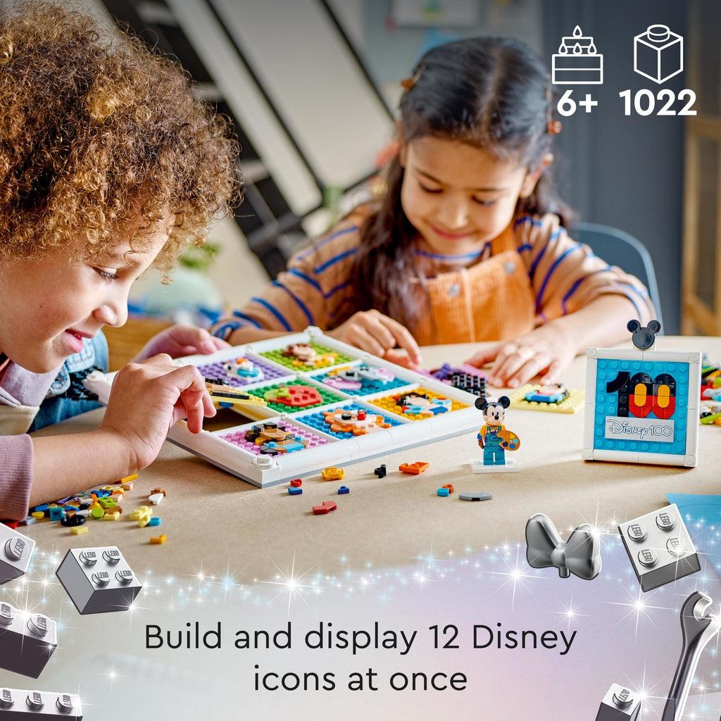 a couple of kids are working together to build the lego set | Piece count of 1022 and age of 6+ shown in top right | Text reads: Build and display 12 disney icons at once