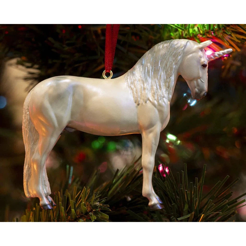 A magical unicorn ornament with a red ribbon. hanging on a tree