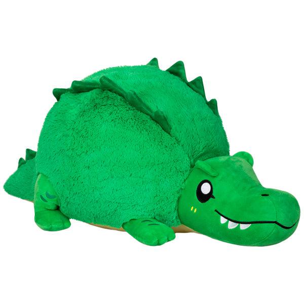 Image of the Alligator squishable. It is a green round plush with embroidered pointy teeth.