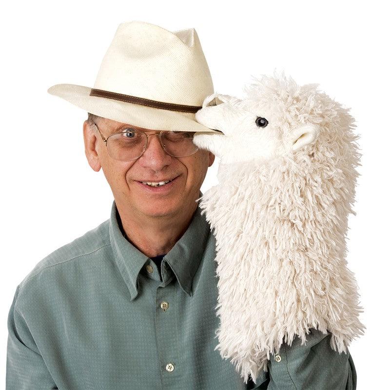 Old man tips fedora with alpaca puppets on hand.