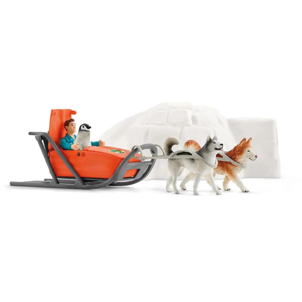 Image of the play set outside of the packaging. It comes with an igloo, an orange snowmobile, a penguin, and two husky dogs.