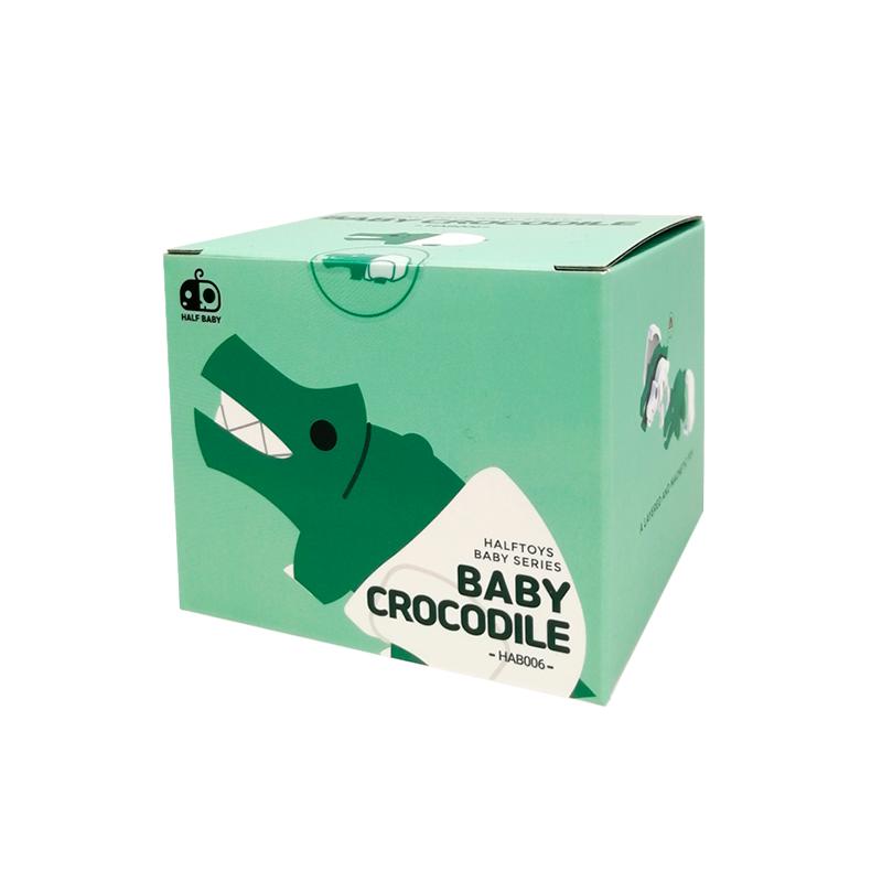 Image of the packaging for the Baby Crocodile and Crib figurine toy. The box is a light green cube and it has a 2D picture of the figurine on the side.