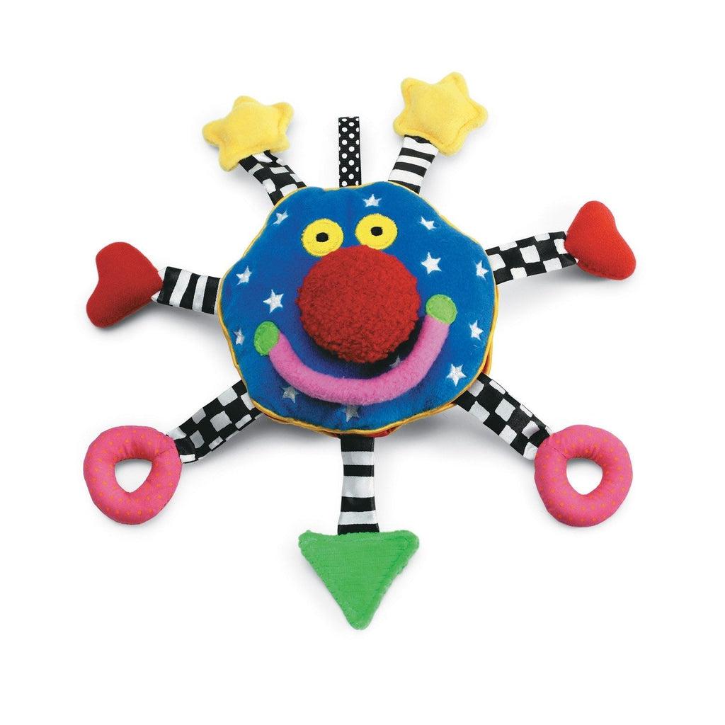 Image of the Baby Whoosit toy. It is a plush teething toy with a blue face, red nose, and yellow eyes. There are seven tags off of the side of his face, each with a different shape at the end. Some of the shapes include a star, a heart, a ring, and a triangle.