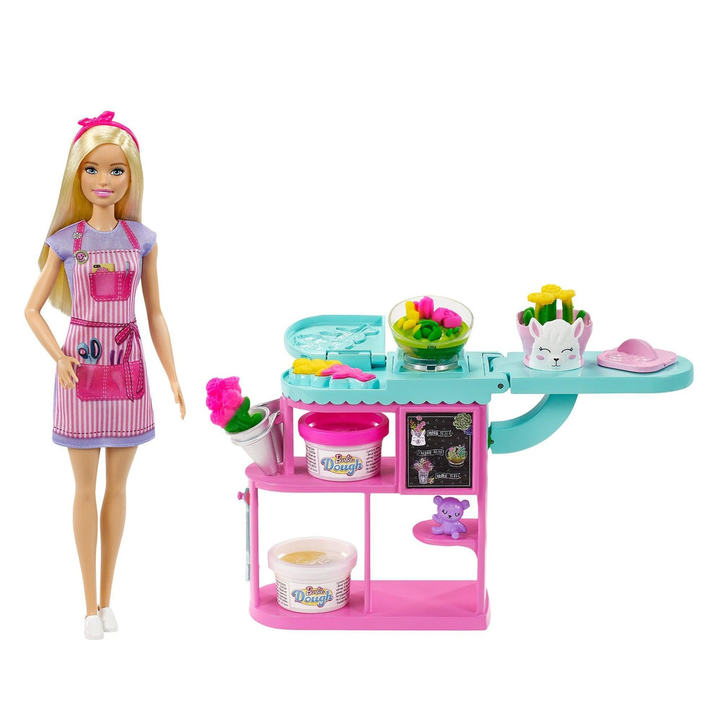 Image of the fully put-together set outside of the packaging. The set includes a Barbie and a flower making station. The station has molds to create the flowers. It can also store the tubs of dough.