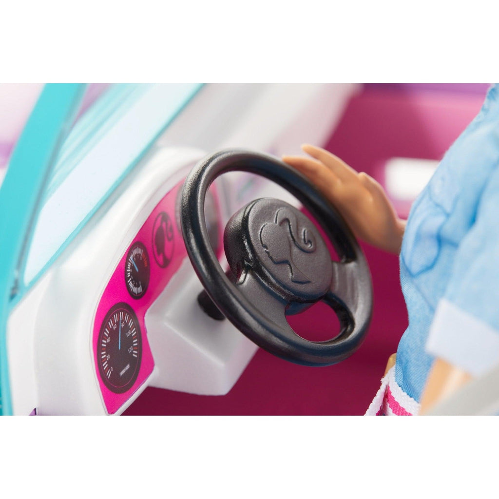 Image of the inside of the vehicle. The interior is pink with a black steering wheel. In the center of the wheel is barbie's logo.