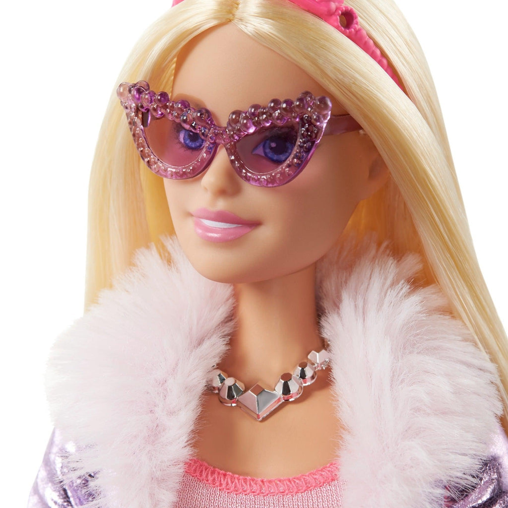 Close up of Barbie wearing purple sunglasses. They have a pointy side so that they are triangular shaped.