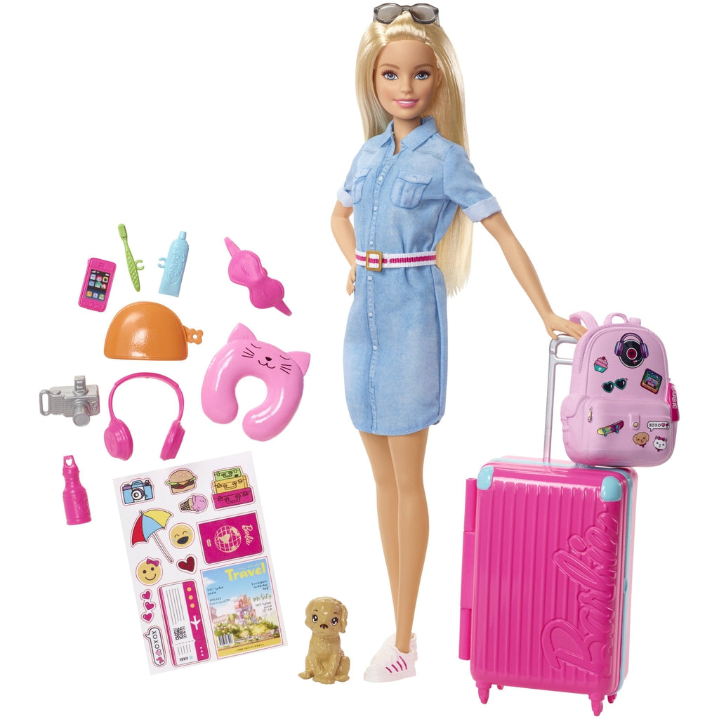 Image of all the included pieces outside of the packaging. The set includes a Barbie, a suitcase and backpack, sitckers, a dog, and various travel items like a neck pillow and a camera.