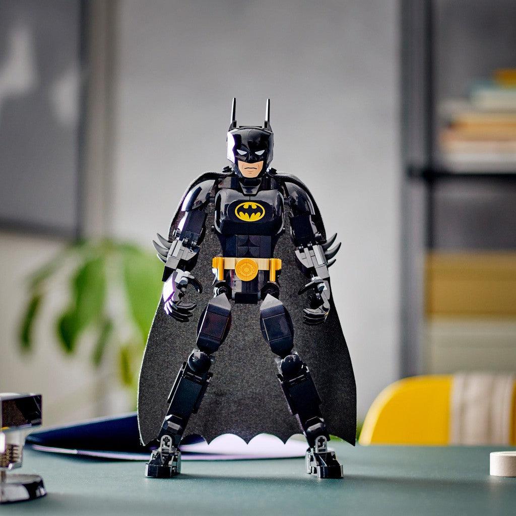 image shows the LEGO batman construction figure standing on a desk, looking ready to fight