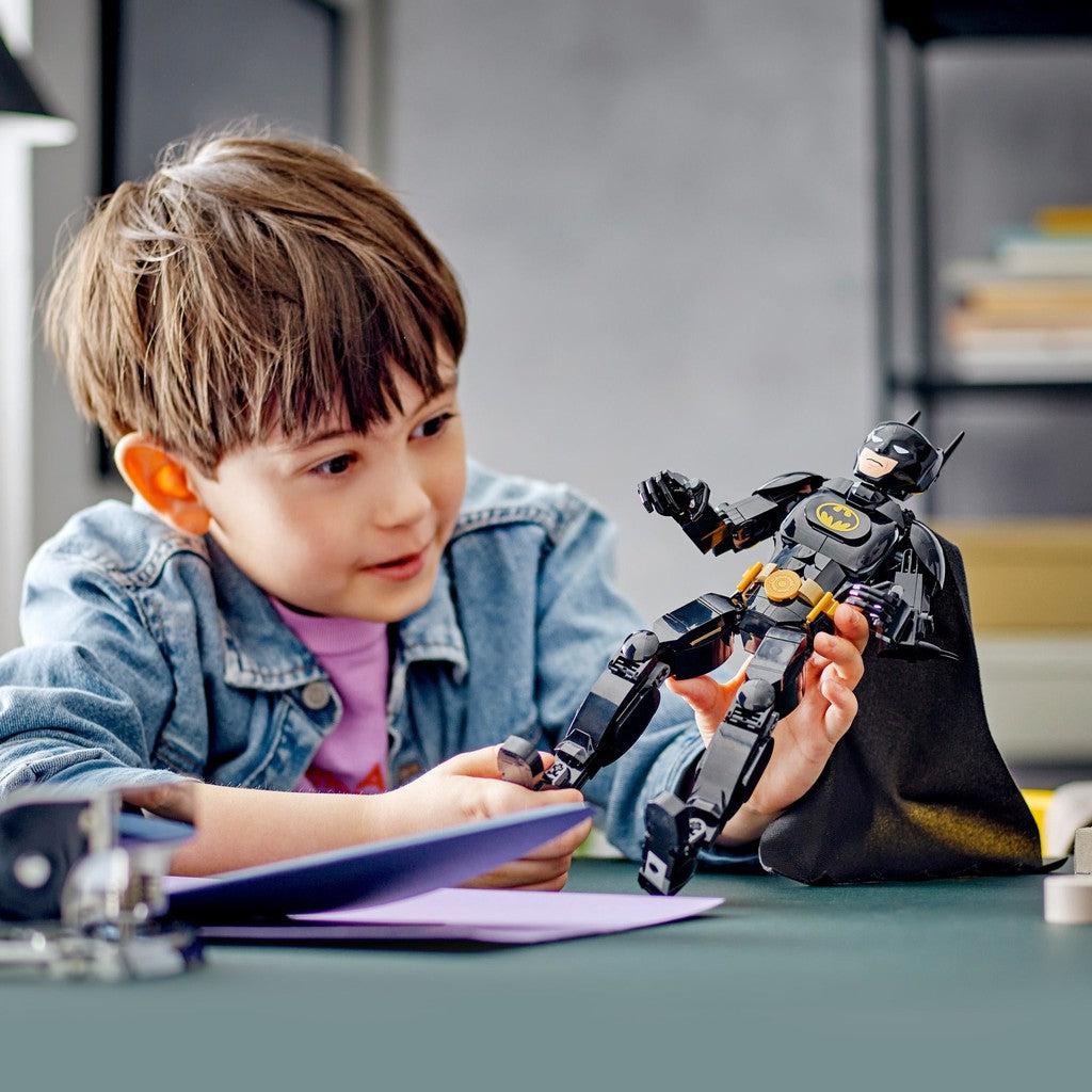 image shows a boy building the batman with the LEGO pieces