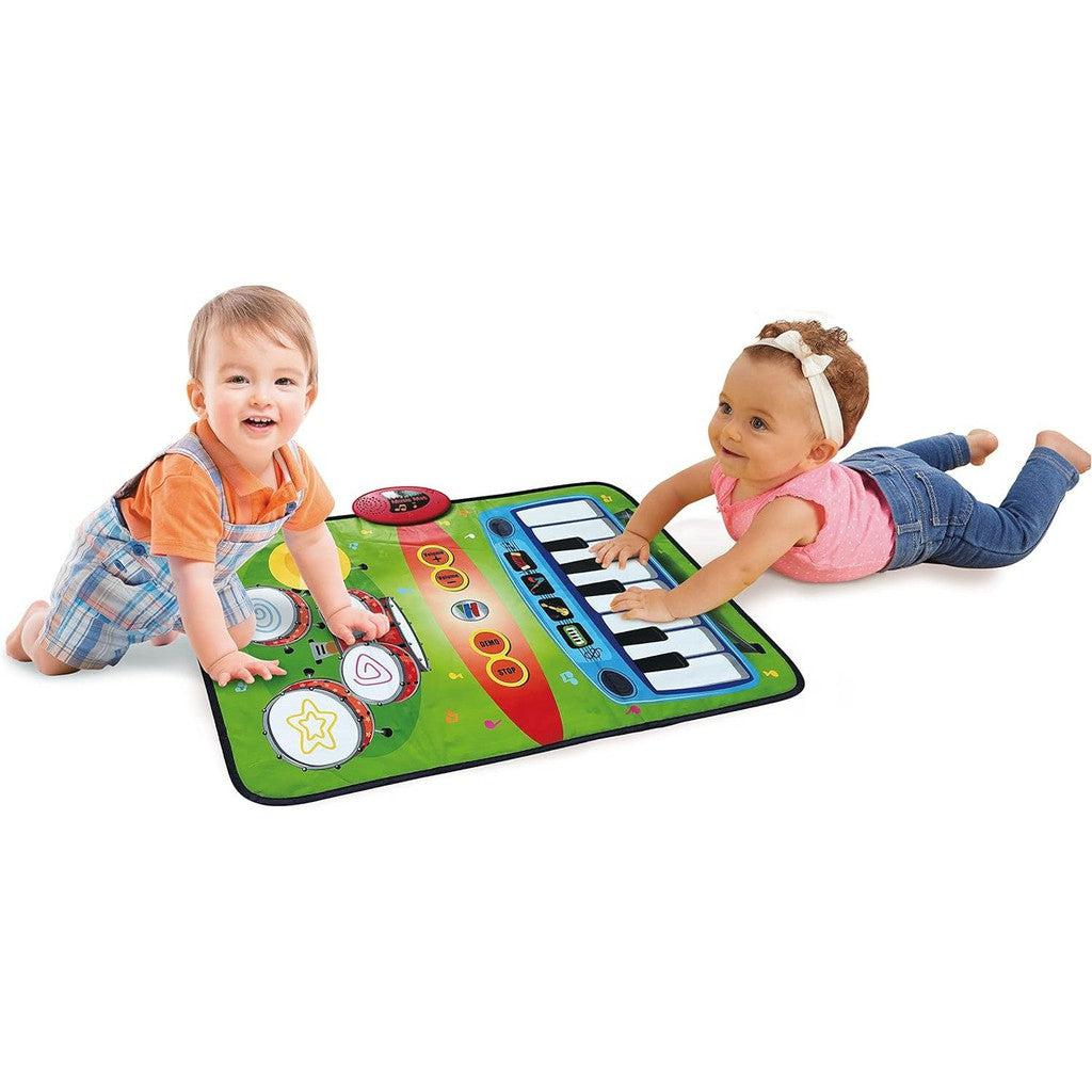 two toddlers are slapping awa\y at the piano and drums on the mat to make sounds as they slap away