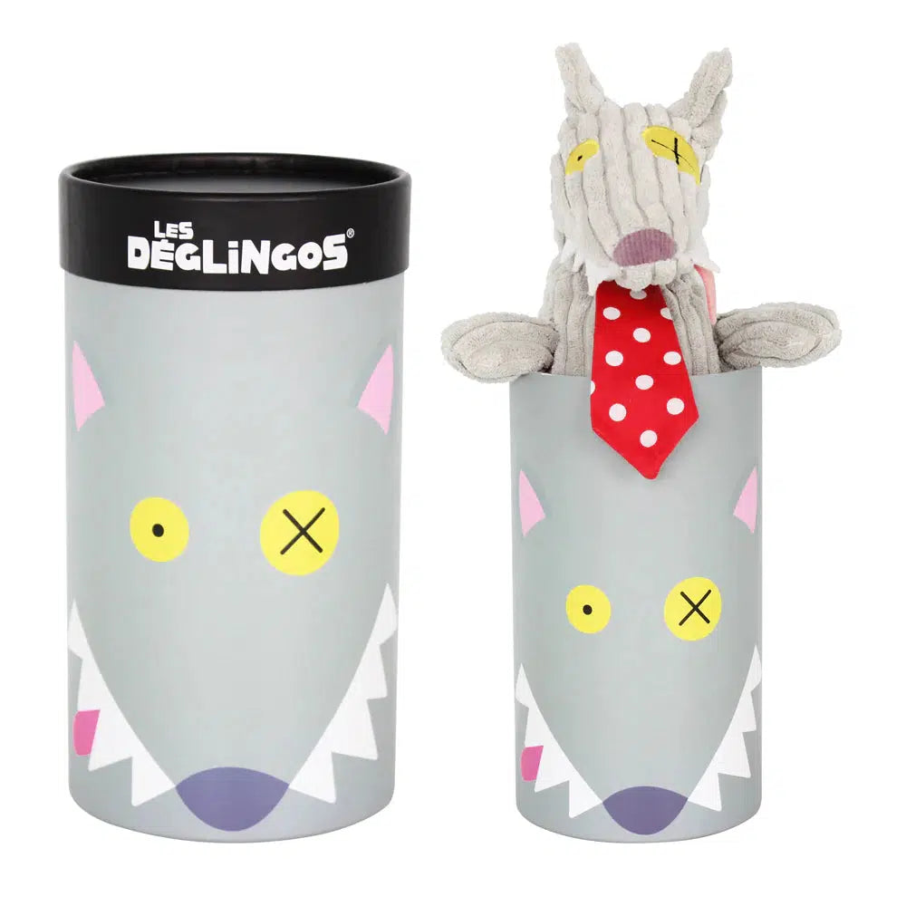 Image of the Big Simply Bigbos the Wolf in Box plush. The box is a cylindrical tube with a cartoon picture of the elements of the plush's face. The plush is a grey wolf with lots of white triangle teeth and a pink tongue sticking out from its mouth. He has two yellow eyes (one has an x on it) and is wearing a red and white polkadotted tie.