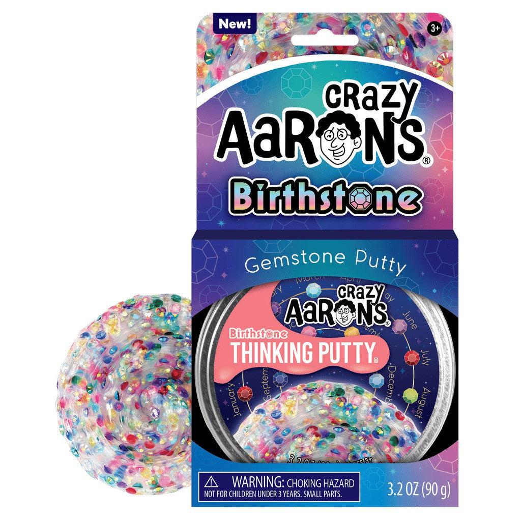 image shows the box and tin for the thinking putty, as well as a glimpse of the putty itself covered in plastic gemstones