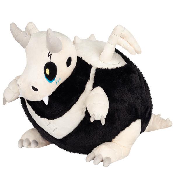 Plush toy resembling a cartoon "Bone Dragon" from, predominantly white and black, with blue eyes and small wings, lying on its stomach.