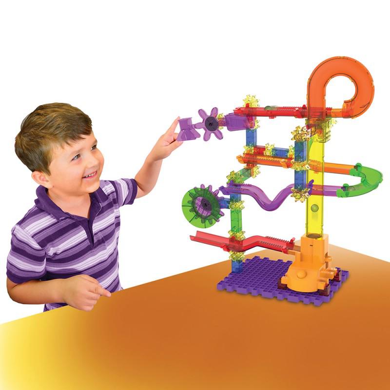 a chils is playing with the marble track, the tower is large and puts marbles on a gear to go around a track.