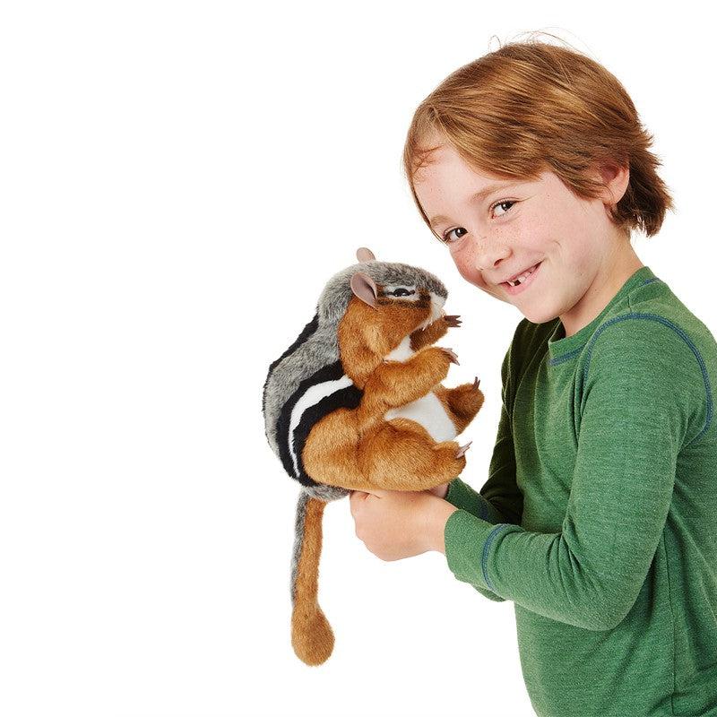 Young boy hold chipmunk puppet on his hand and gives the camera a mischeivious look.