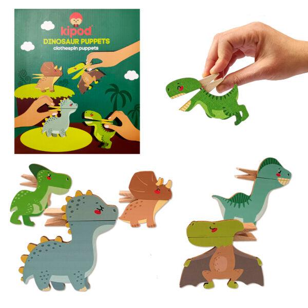 A hand holding a green clothespin puppet in the shape of a dinosaur, with a box labeled "Kipod Dinosaur Puppets" and other wooden dinosaur puppets displayed, perfect for imaginary play in your very own Clothespins Theater Puppet show.