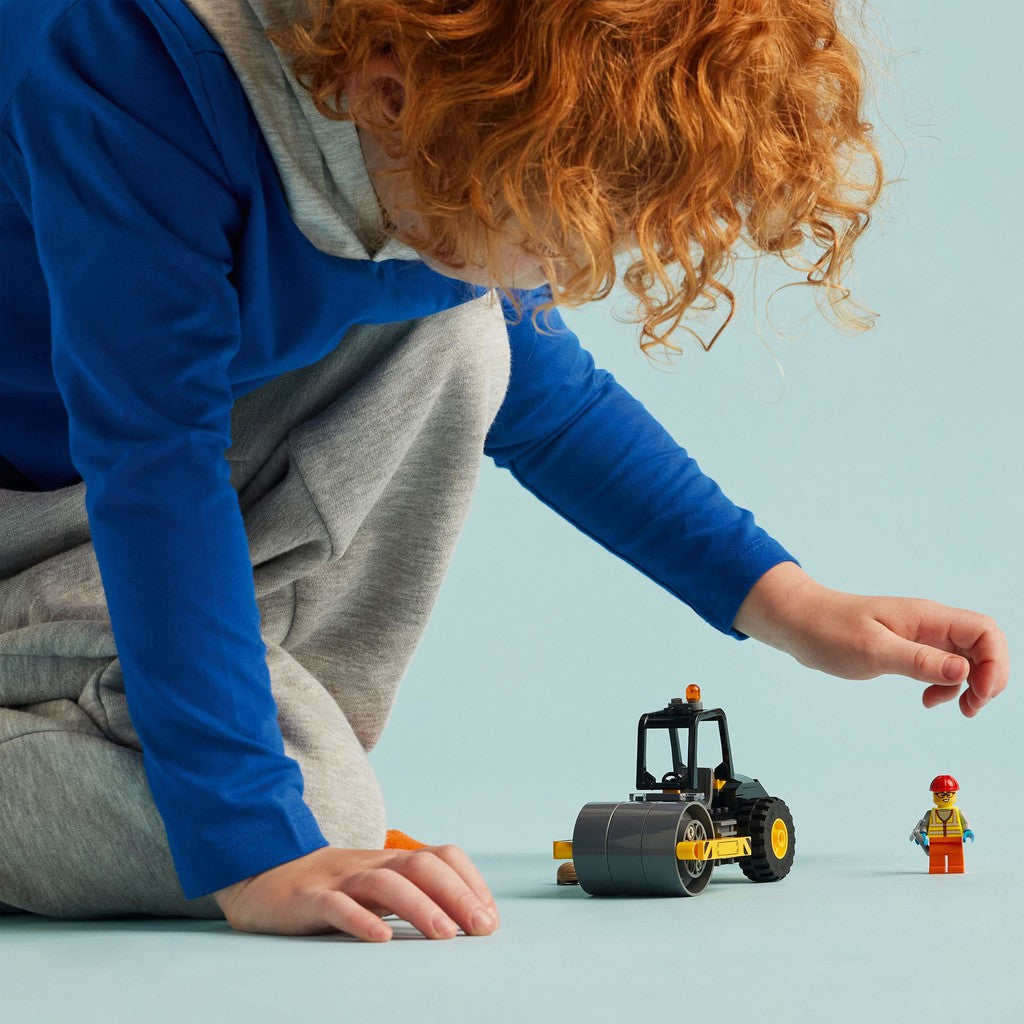 a child is playing with the steamroller and minifigure