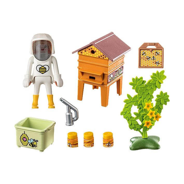 picture shows everything in the box, the bee hut, a  crate for the files of boneycomb, the beekeeper, plants, jars of honey, and a spray to keep the bees healthy. 