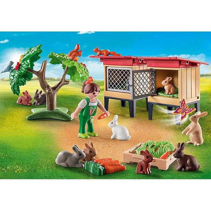 This picture shows more detail to the contents of the box, there is a person feeding a rabbit, four rabbits grazing on carrots, a rabbit chasing a butterfly, one resting in the hutch, two resting by a tree while squirrels run around on the tip of the tree. 