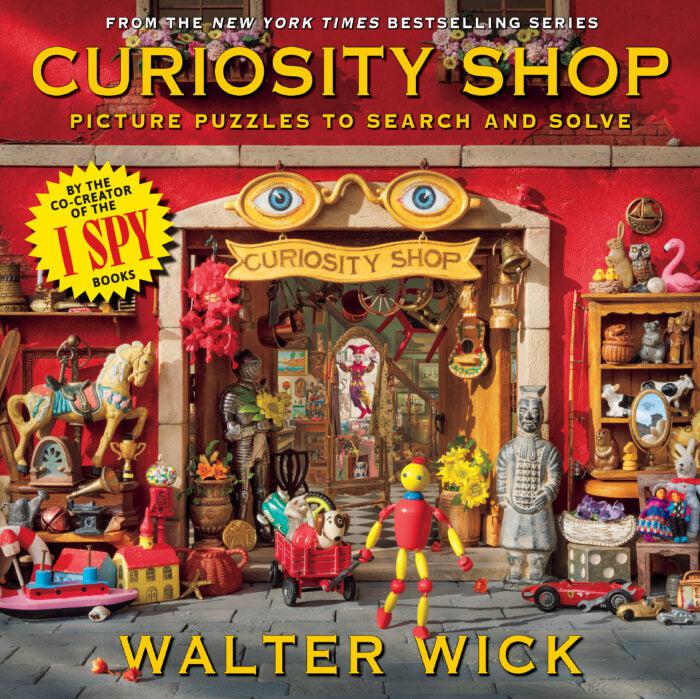 An I Spy Book called Curiosity Shop. Picture puzzles to search and solve feature a wide array of items arranged to look like a tiny shop with a tiny man made of beads in front.