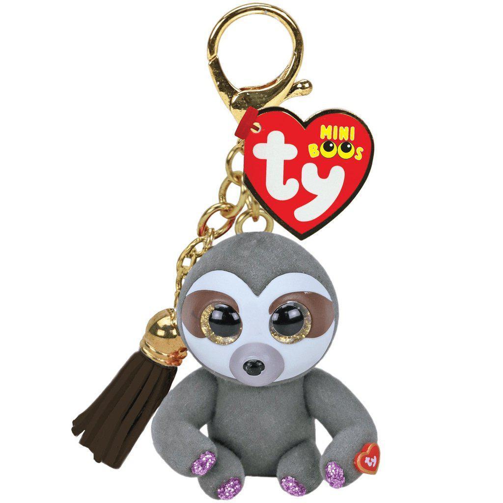 Image of the Dangler the Sloth Keychain. It is a hard grey sloth with a white and brown face. It has glittery purple paws and is attached to a gold keychain clip.
