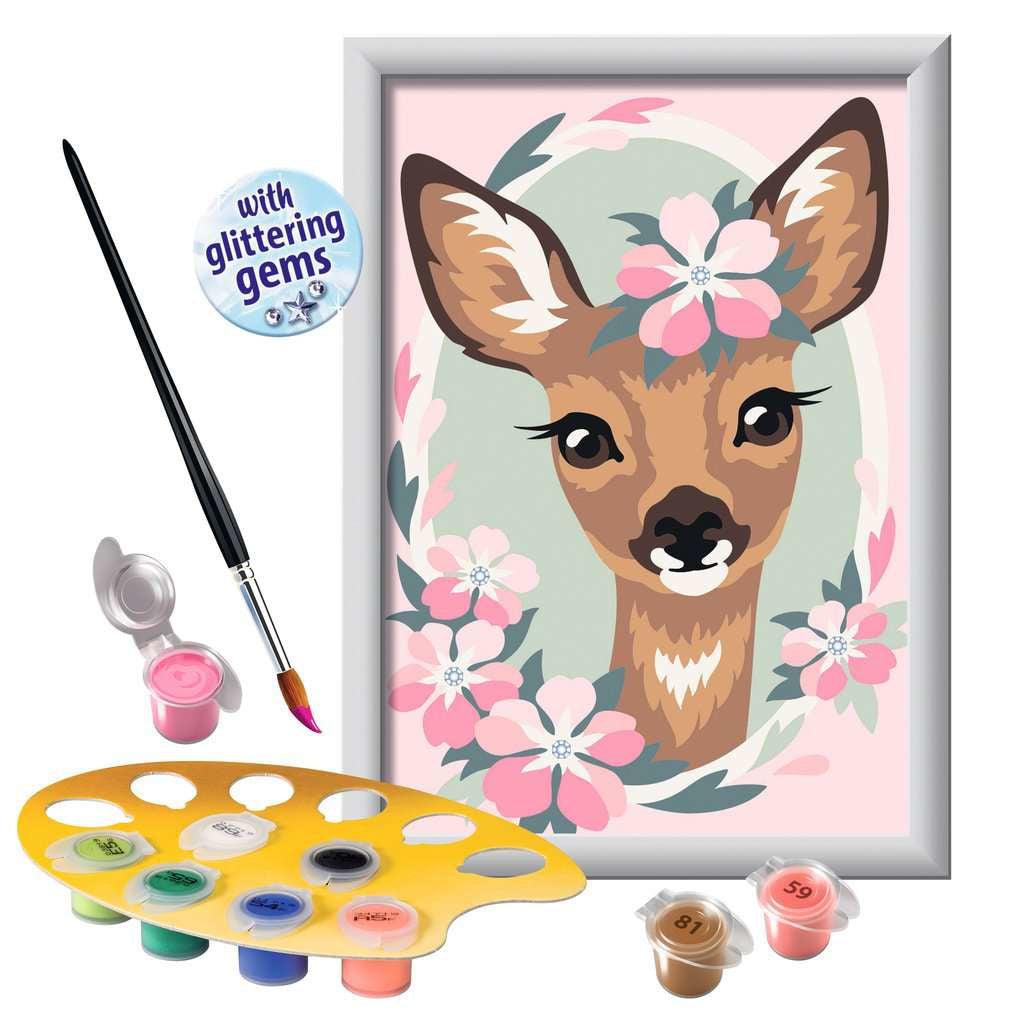 The picture shows a stencil holding all the paint while a paintbrush is dipped in pink to add some blossoms to the deer adding a lovely accent. 
