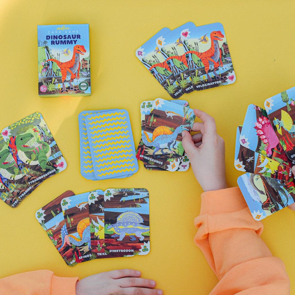 a child is playing rummy with dinosaurs, collecting the cards he needs. 