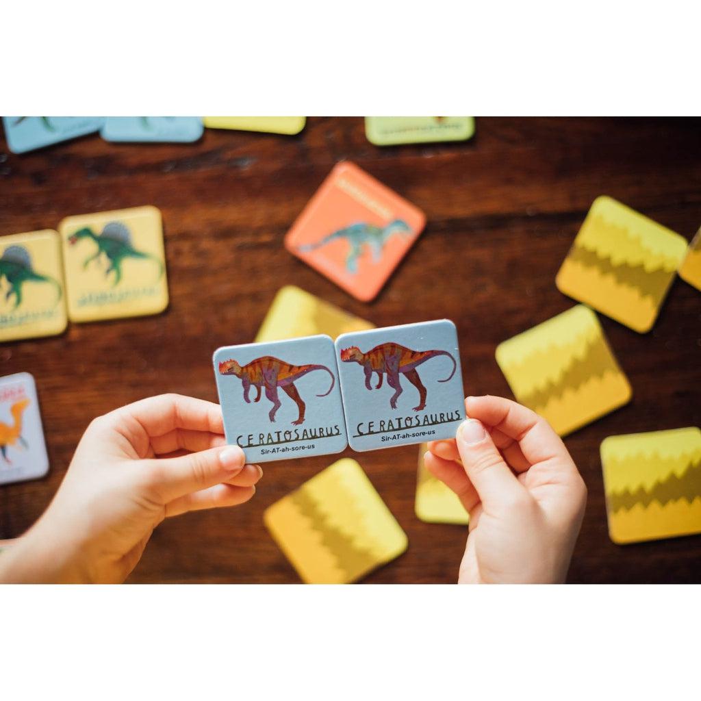 a picture of two ceratosaurus's are next to each other in a small hand to show how the matching game works, other cards are upside down
