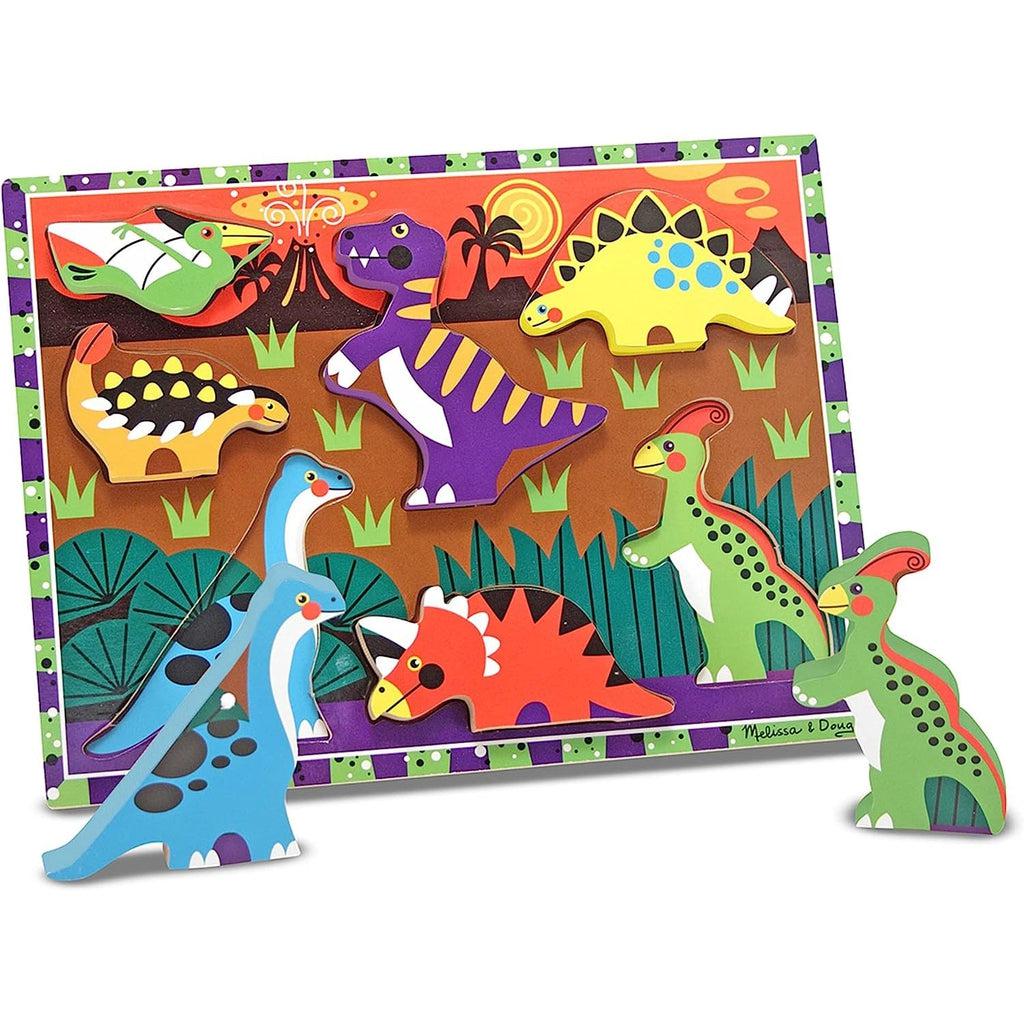 Image of the wooden puzzle board. The background board has a prehistoric scene with a ovlcano errupting in the background. It has wooden dinosaur puzzle pieces of different species.
