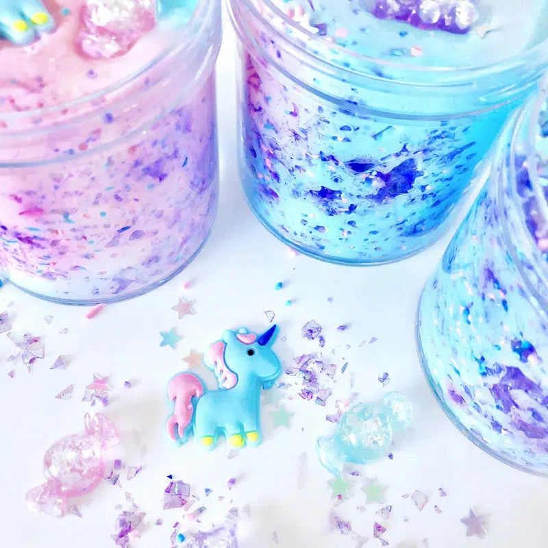 this image shows a unicorn not in slime surrounded by glitter with containers of slime around the unicorn. the unicorn is blue with a pink tail. 