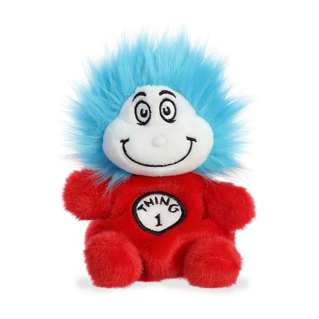 Image of the Dr. Seuss Thing 1 Palm Pal plush. It has a red body, a white face, and electric blue hair. It has a smiling face and a sign saying "Thing 1" on its chest.