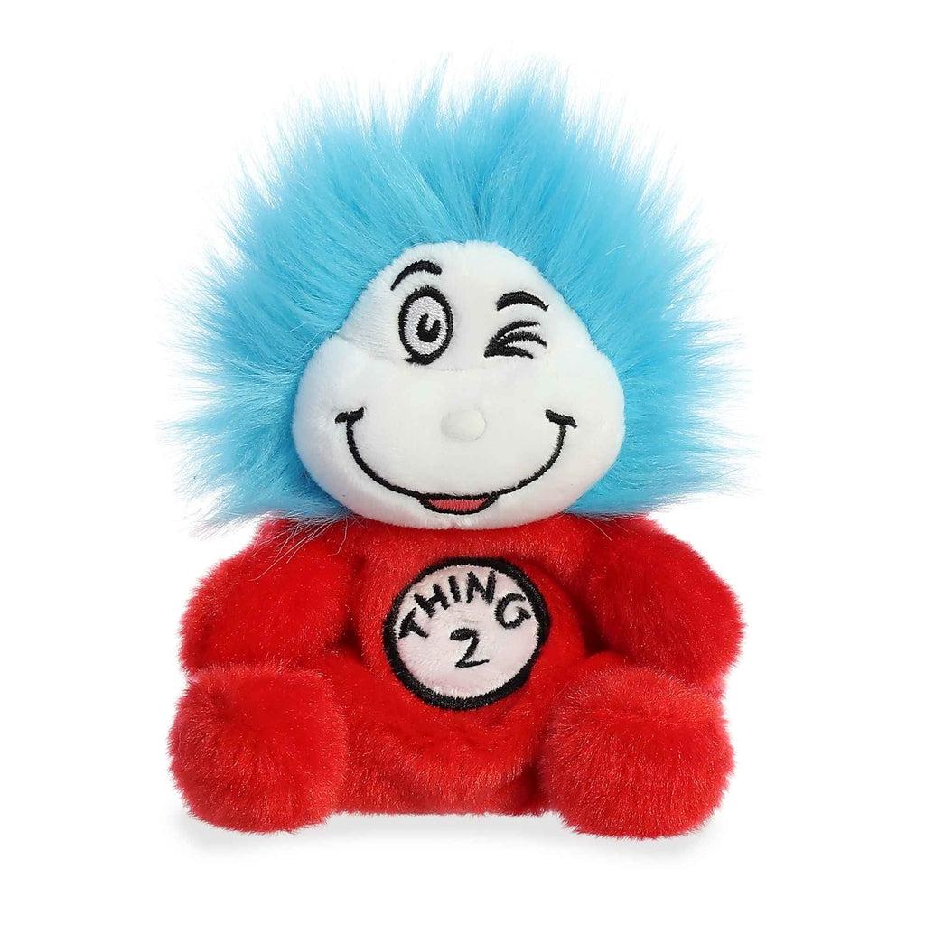 Image of the Dr. Seuss Thing 2 Palm Pal plush. It has a red body, a white face, and electric blue hair. It has a smiling face with one eye winking. On his chest is a sign that says "Thing 2"